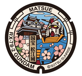 An image of the Gundam manhole cover design installed in Matsue City, Shimane Prefecture. The design features Matsue Castle, a national treasure located in the city.